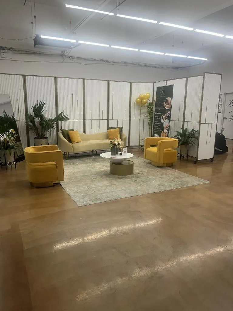 Elegant waiting area in Be You Esthetic Suites with yellow armchairs, a coffee table, and decorative plants.