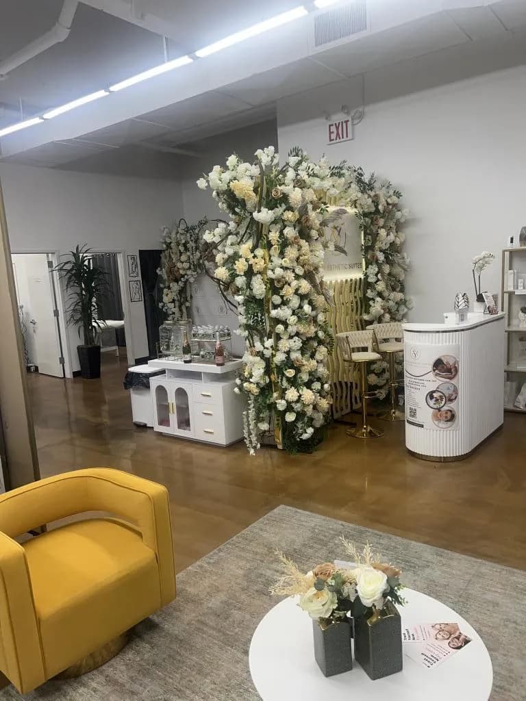 Luxurious med spa interior at Be You Esthetic Suites featuring floral decor, a stylish yellow chair, and treatment stations.