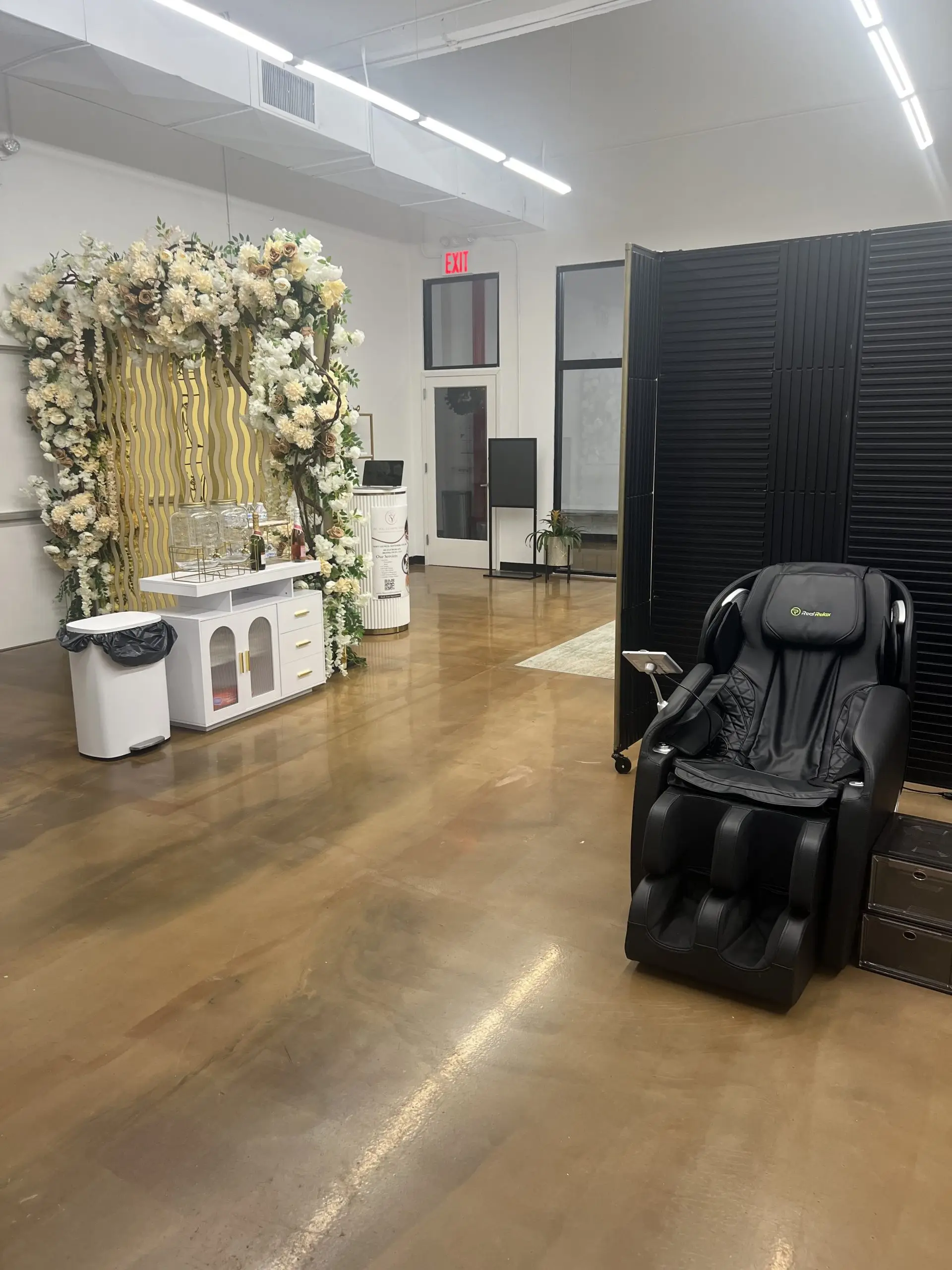 Interior of a luxurious med spa suite featuring a floral backdrop, treatment station, and massage chair.